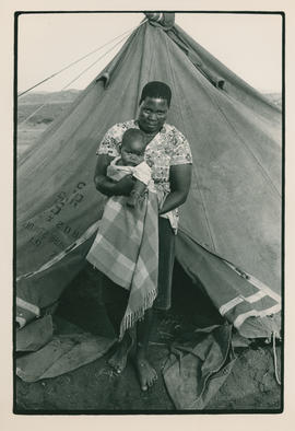 Women with a baby outside tent.