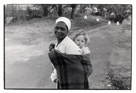 Domestic worker with white child on her back